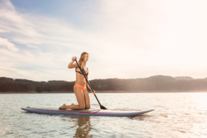 Athletic Women Paddle Boarding on the Lake in Summertime