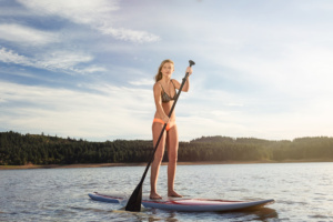 Athletic Women Paddle Boarding on the Lake in Summertime